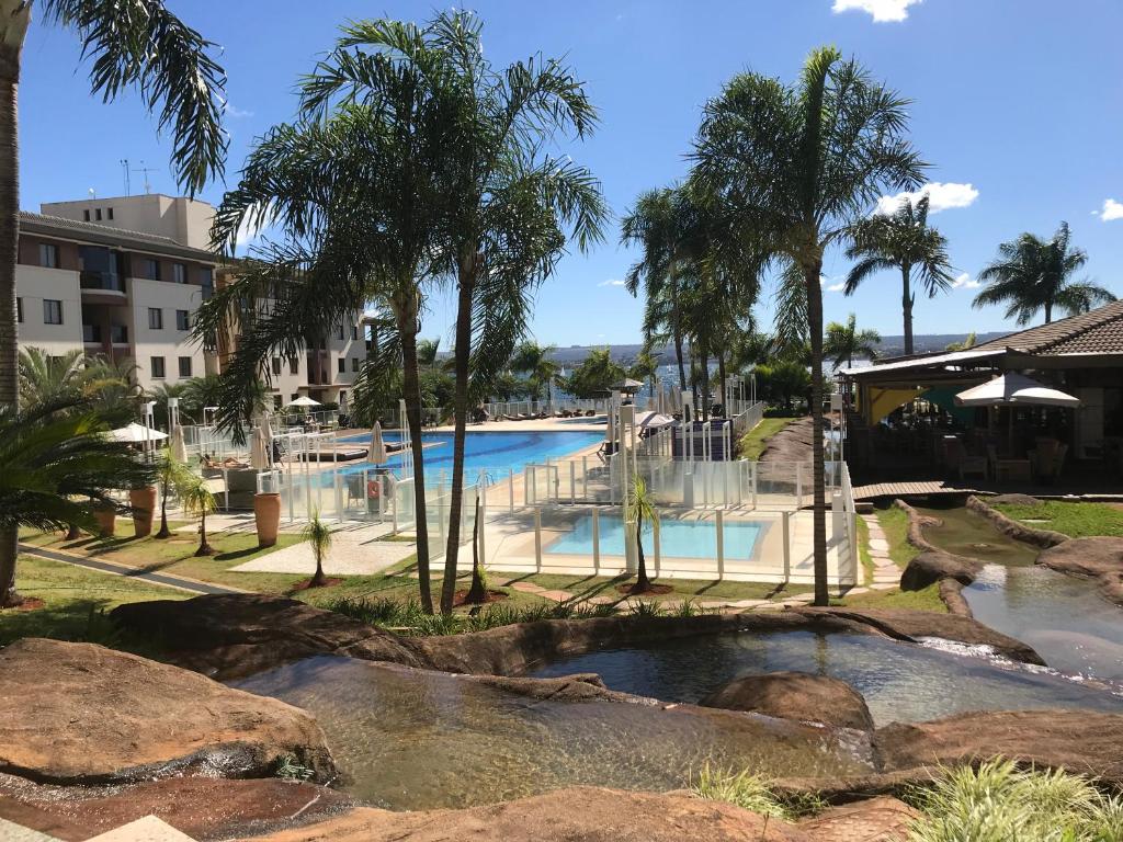 uma piscina num resort com palmeiras em Flat em Resort incrivel a 10 min da Esplanada, STF e PGR em Brasília