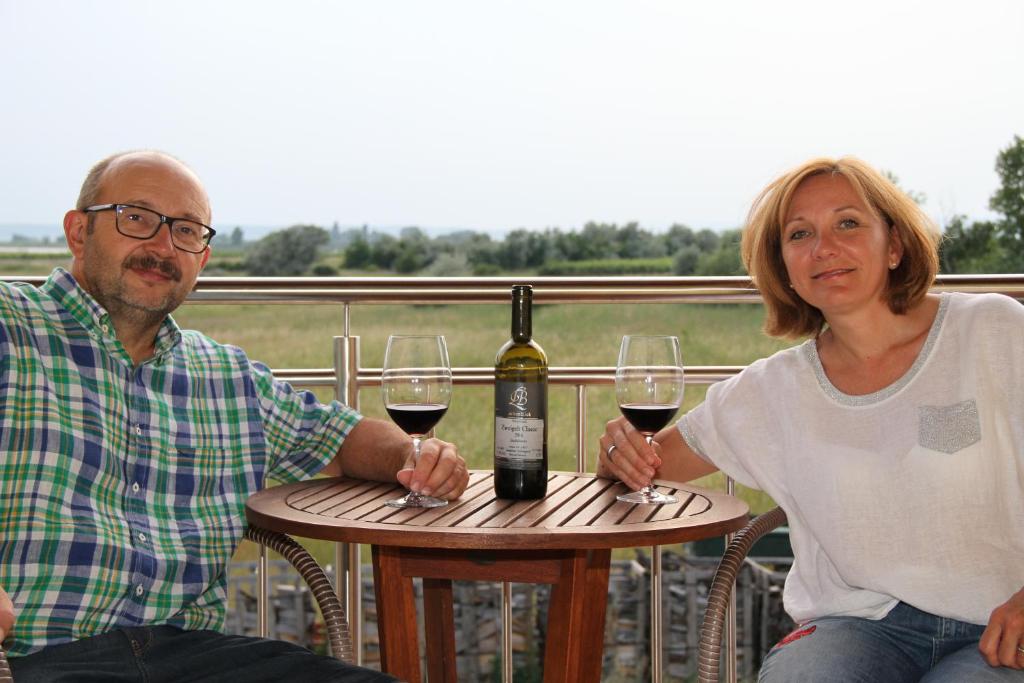 mężczyzna i kobieta siedzący przy stole z kieliszkami do wina w obiekcie Gästehaus Lackenblick w mieście Illmitz