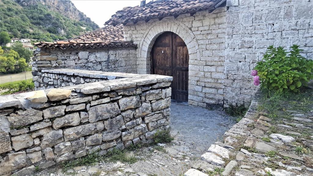 kamienny budynek z drewnianymi drzwiami i kamienną ścianą w obiekcie Dhimitri's guest house w mieście Berat