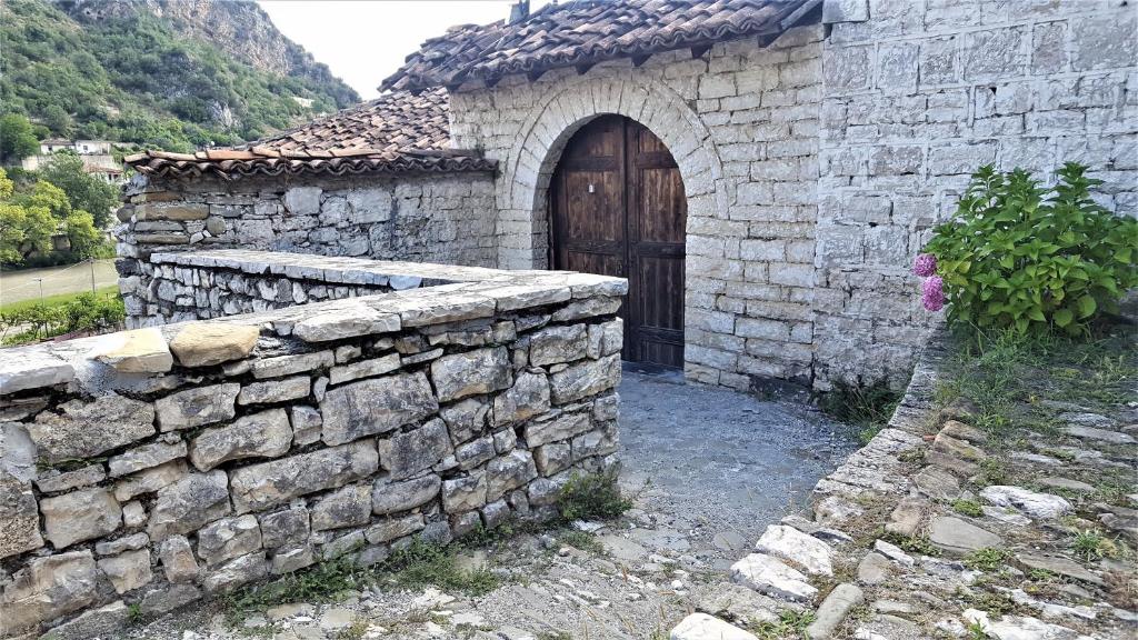 a stone building with a wooden door and a stone wall at Dhimitri's guest house in Berat