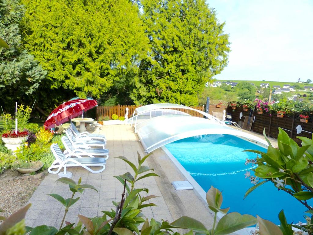 una piscina con sillas y una sombrilla roja en Domaine du Parc en Montsoreau