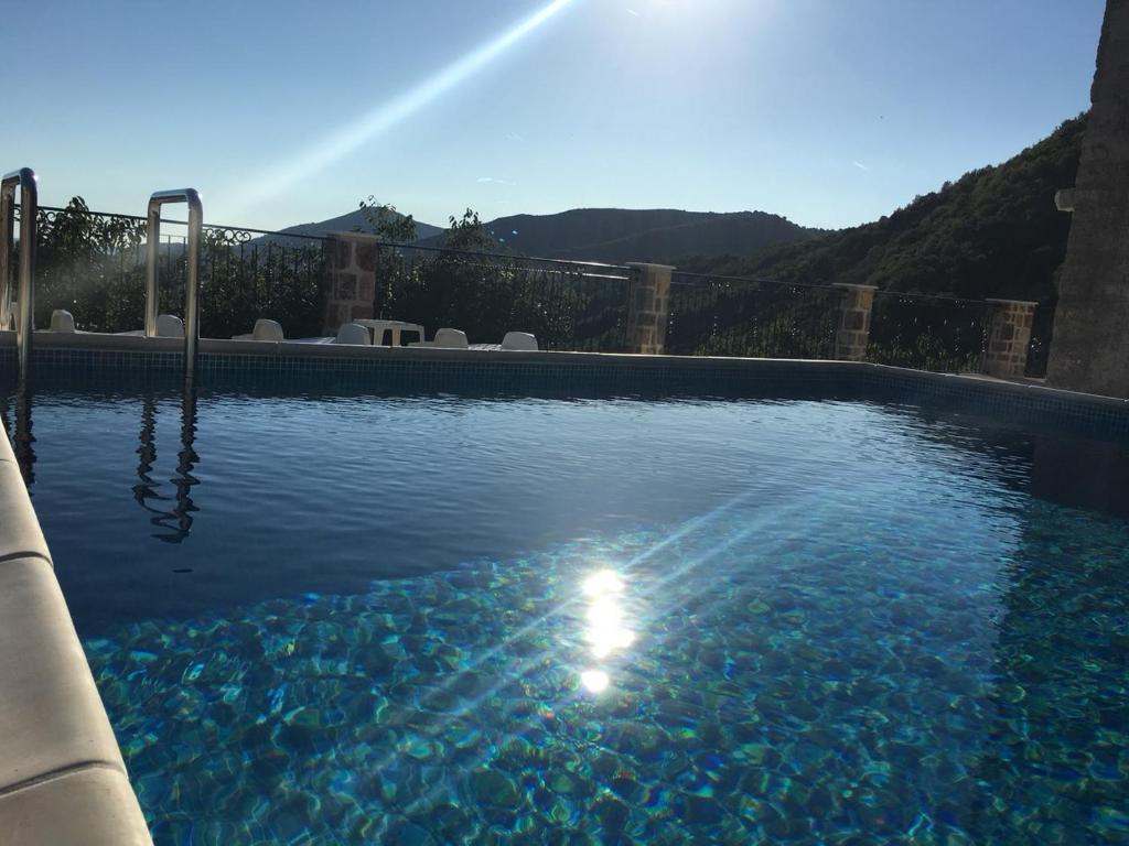 a swimming pool with the sun shining in the water at Luka Villa in Becici