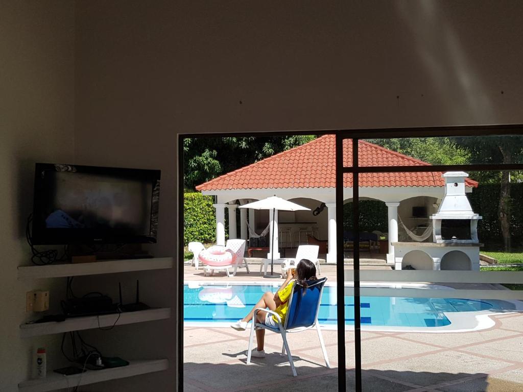 a woman sitting in a chair next to a swimming pool at Casa Hacienda El Imperio in Carmen de Apicalá