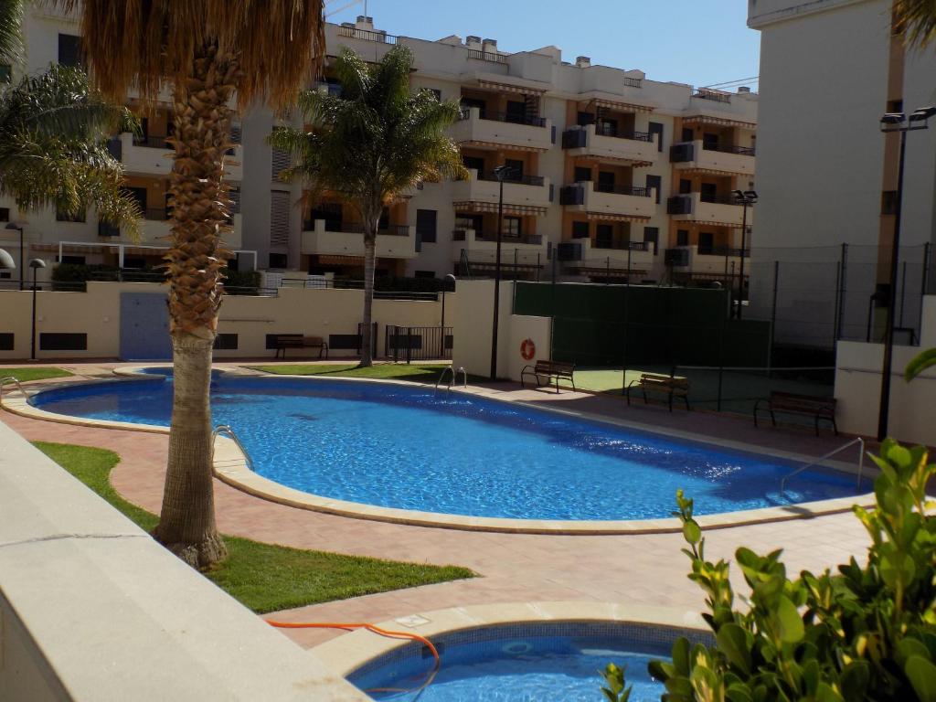 una piscina con una palmera frente a un edificio en Apartamento impecable en playa de Almenara, en Almenara