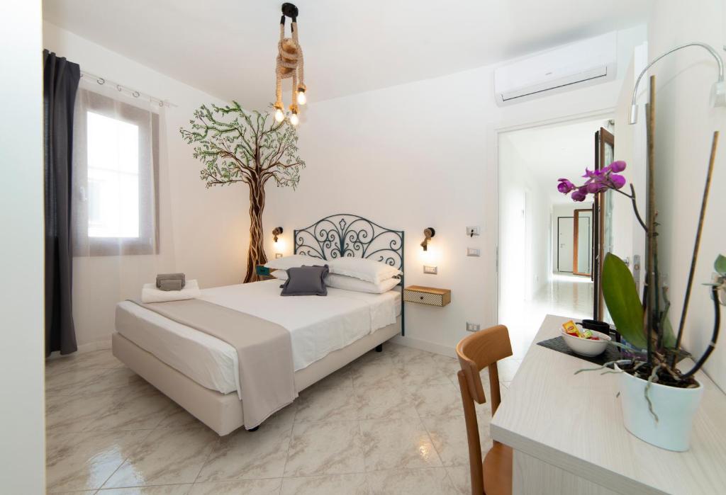 a white bedroom with a bed and a tree on the wall at B&B Mario Relais in Sorrento