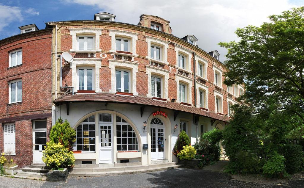 ein großes Backsteingebäude mit einer weißen Tür in der Unterkunft Hôtel de France in Lillebonne