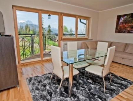 een eetkamer met een glazen tafel en stoelen bij Apartament Kolodziej in Zakopane