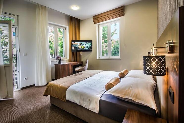 a bedroom with a large bed with a desk and windows at Central Luxury Rooms in Omiš