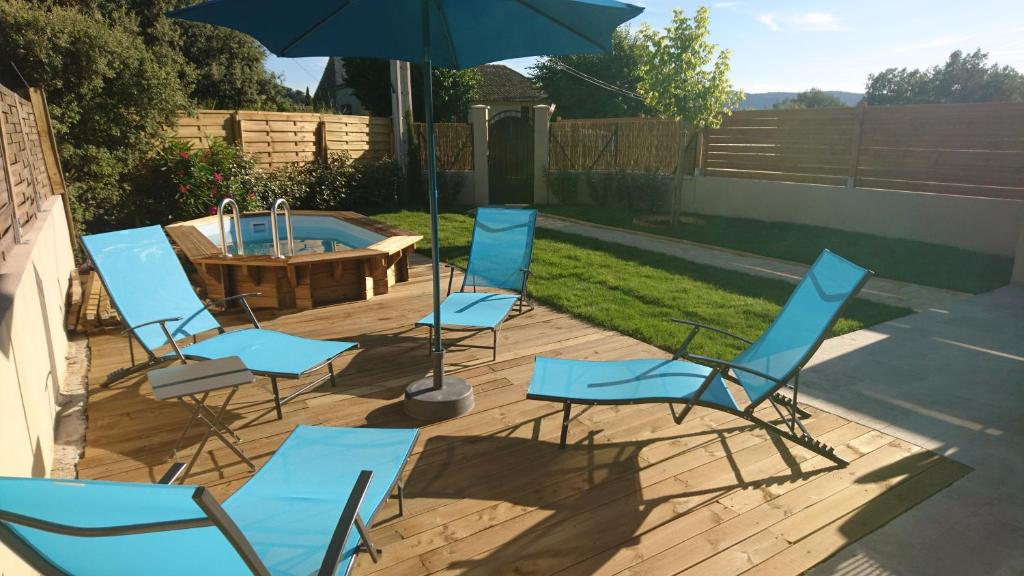 een groep stoelen en een parasol op een patio bij LES LAUZES DE ST MICHEL-LA SARRIETTE in Entrechaux