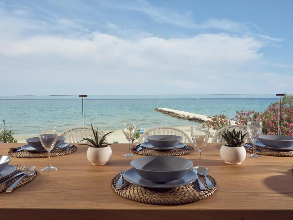 einen Holztisch mit Tellern und Gläsern am Strand in der Unterkunft Maritimus Excelsior in Alykes