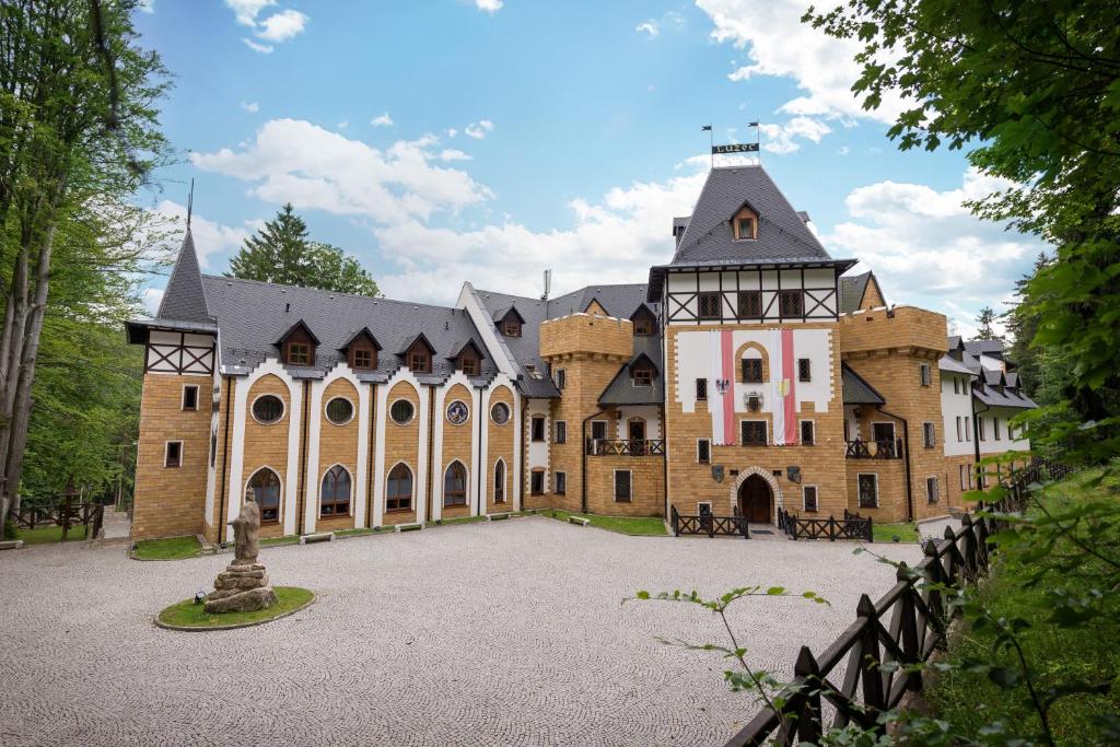 um grande edifício de tijolos com um telhado preto em Zámek Lužec Spa & Wellness Resort em Karlovy Vary