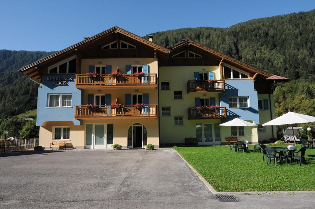 a large building with tables and chairs in front of it at Residence Alice in Celledizzo