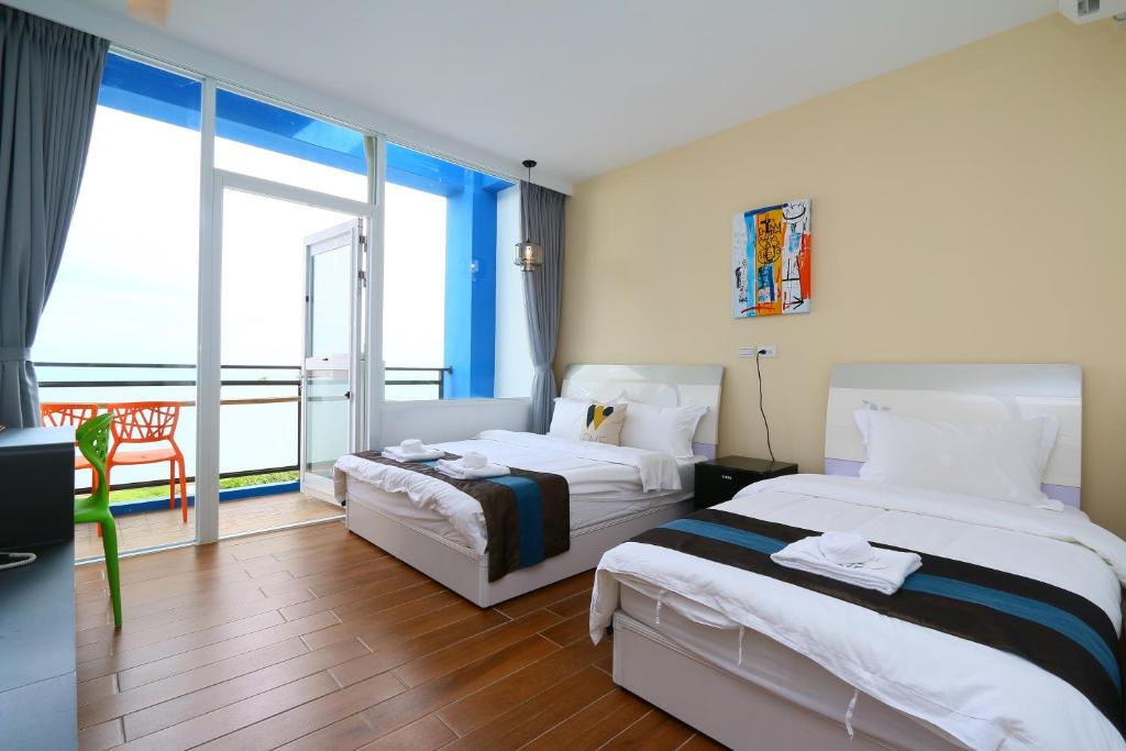 a hotel room with two beds and a balcony at Hiinn B&B in Hualien City