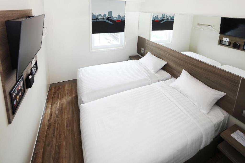 two twin beds in a room with a tv at Red Planet Manila Binondo in Manila