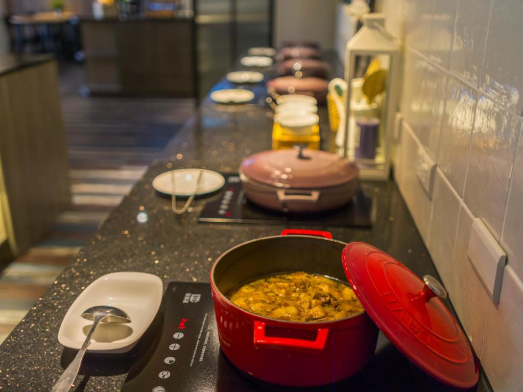 a counter with a pot of food on a table at Watermark Hotel - Sizihwan in Kaohsiung