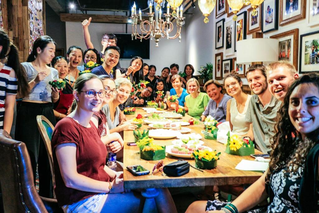een groep mensen die rond een tafel zitten bij Sonderia Hostel & Bar - Lazybones Hostel in Chengdu