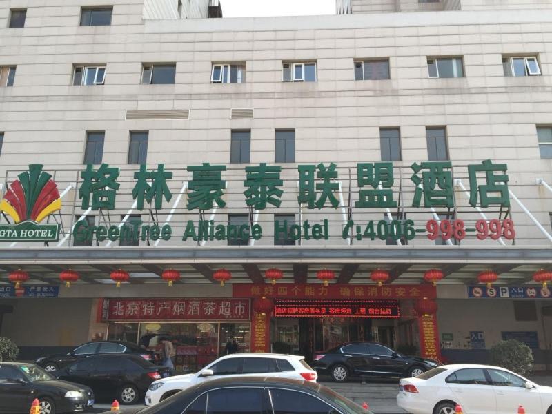 a building with a sign on it with cars parked in front at Greentree Alliance Beijing West Railway Station Zhanqian North Square Hotel in Beijing