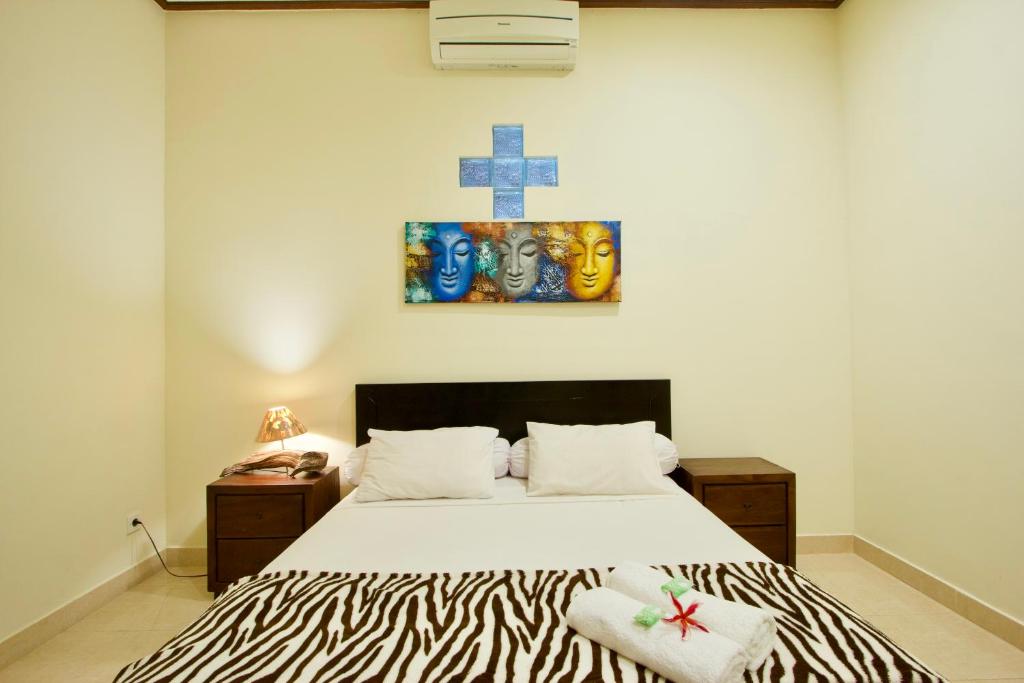 a bedroom with a bed and a cross on the wall at Jepun Bali Homestay Sanur in Sanur