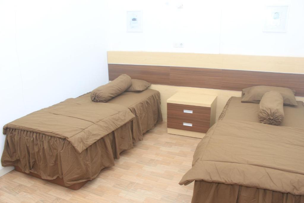 a bedroom with two beds and a wooden floor at Aurora Guest House in Wonosobo