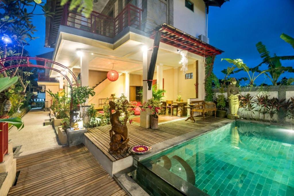 a villa with a swimming pool and a house at Metteyya Healing House in Ubud