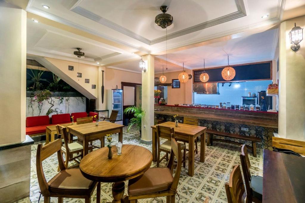 a restaurant with wooden tables and chairs and a bar at Metteyya Healing House in Ubud