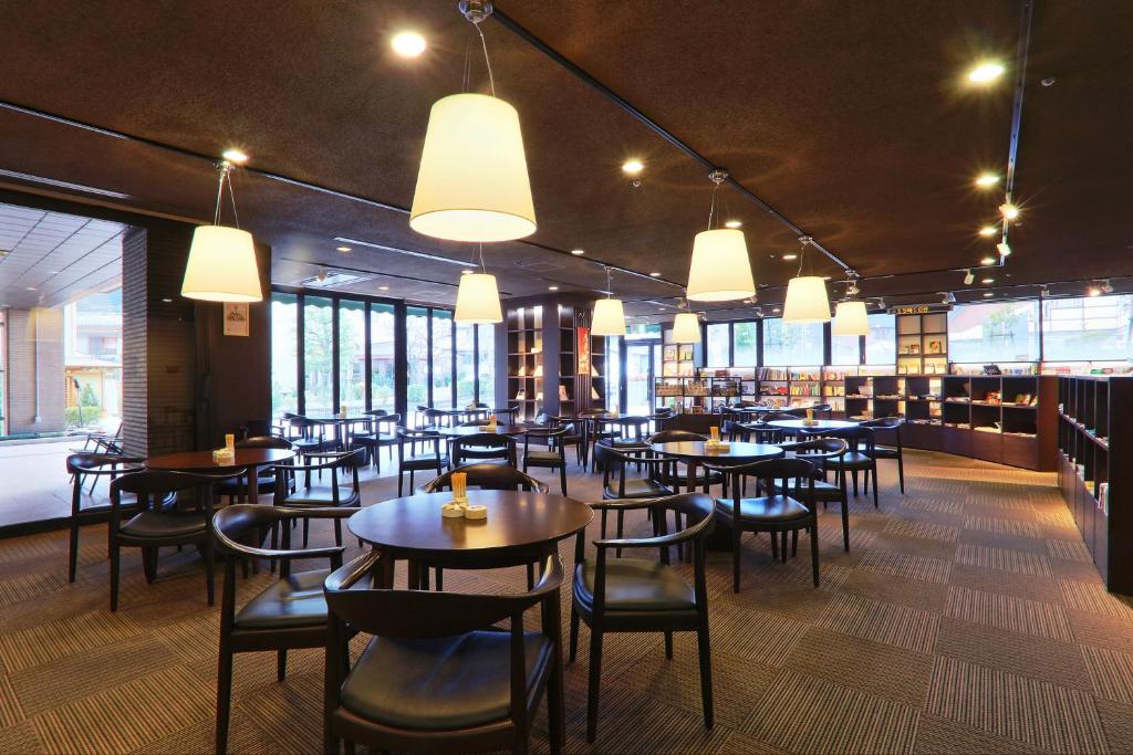 a dining room with tables and chairs and windows at Hotel Binario Saga Arashiyama in Kyoto