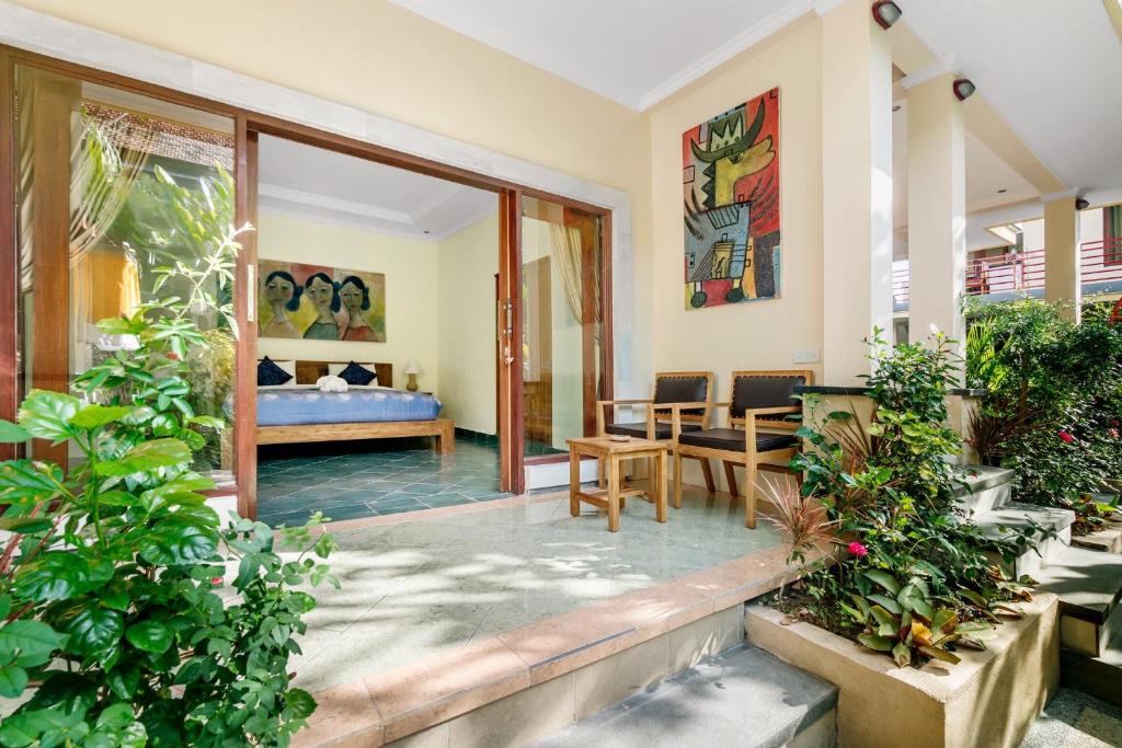 a room with a bed and a room with plants at Metteyya Healing House in Ubud