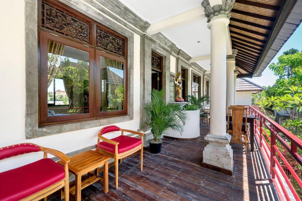 a porch with red chairs and a red railing at Metteyya Healing House in Ubud