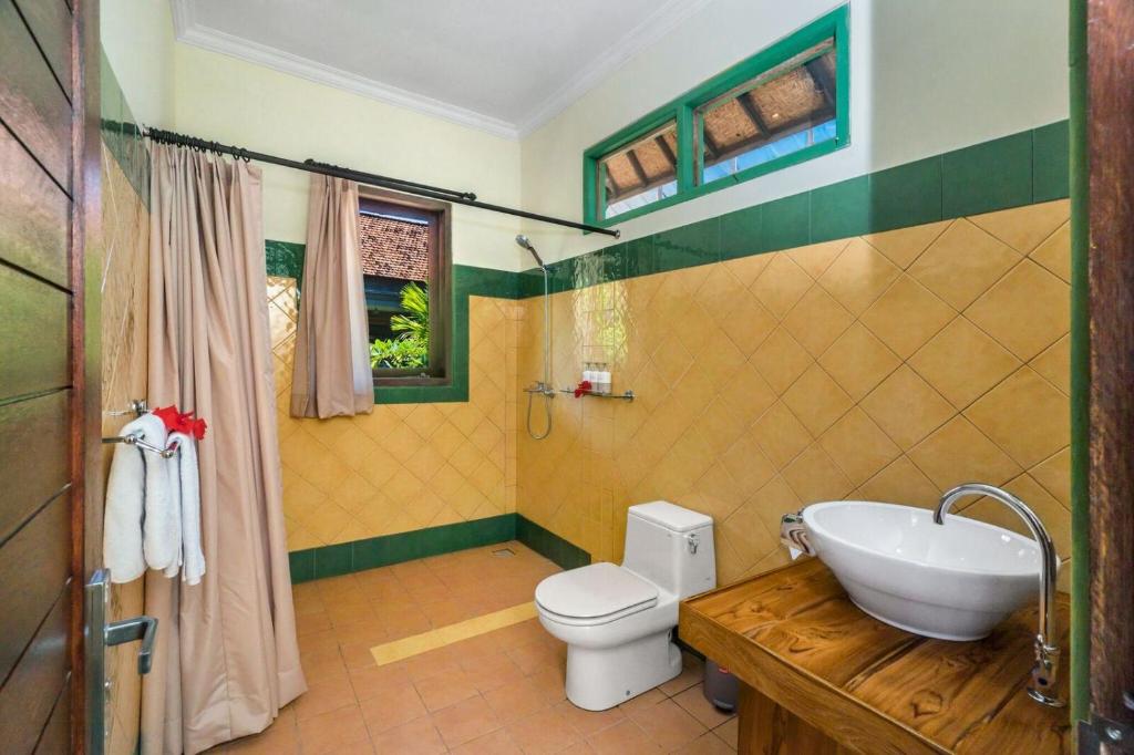a bathroom with a white toilet and a sink at Metteyya Healing House in Ubud