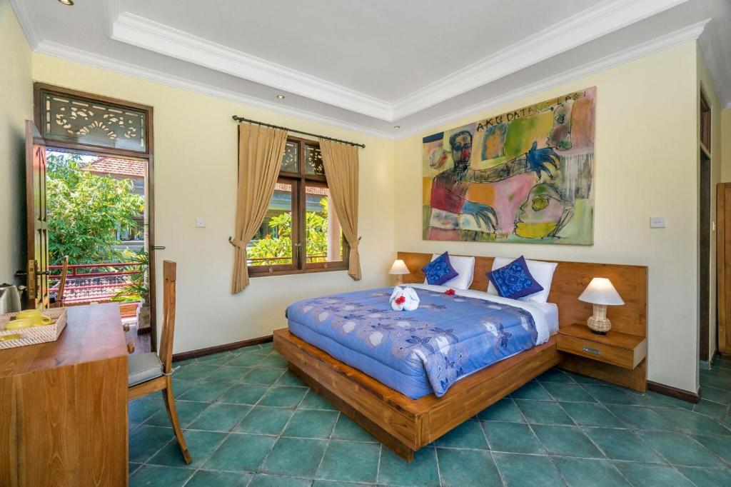 a bedroom with a bed and a desk and two windows at Metteyya Healing House in Ubud