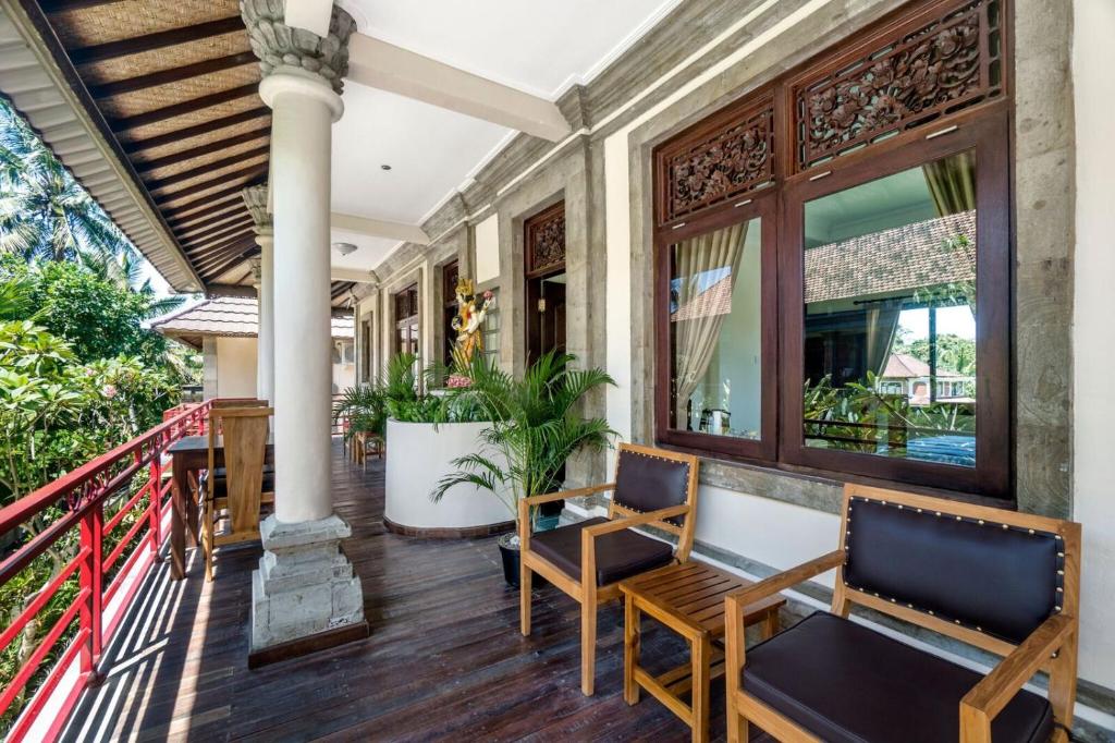 a porch of a house with two chairs and a table at Metteyya Healing House in Ubud