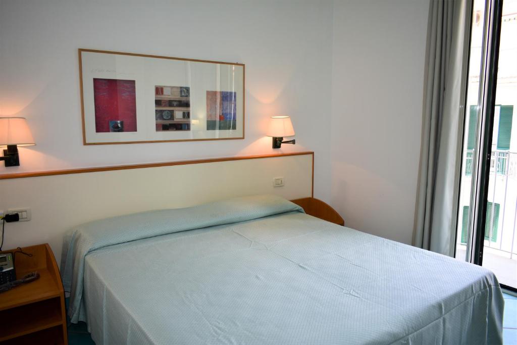 a bedroom with a bed and a mirror on the wall at Hotel Amyclae in Sperlonga