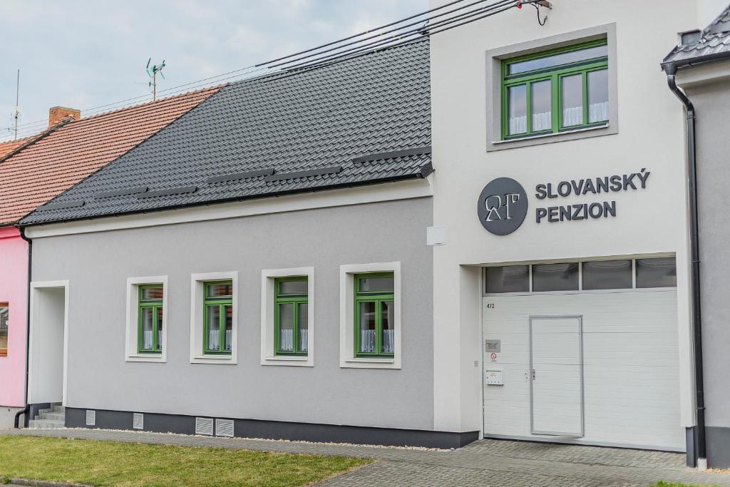 un bâtiment blanc avec un toit gris et un garage dans l'établissement Slovanský penzion, à Mikulčice