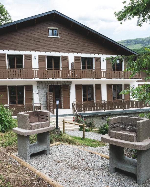 a building with two stone benches in front of it at Au chalet des quatre saisons in Ax-les-Thermes