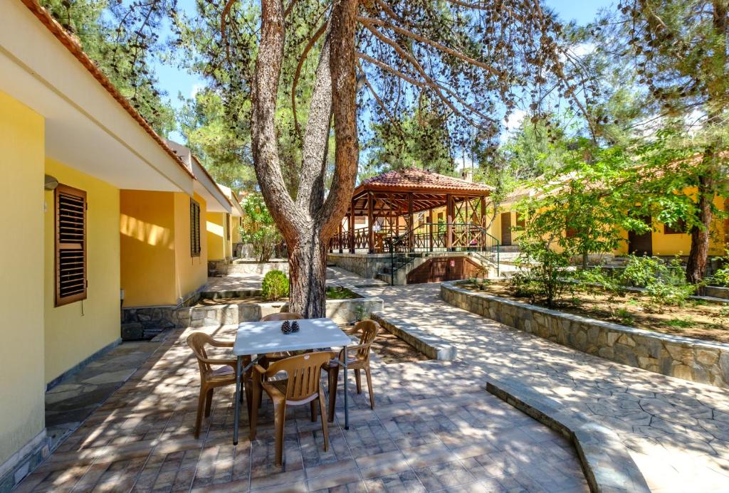 un patio con mesa, sillas y un árbol en Platres Valley Houses, en Platres