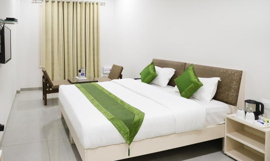 a bedroom with a large white bed with green pillows at Itsy By Treebo - Kamron in Chandīgarh