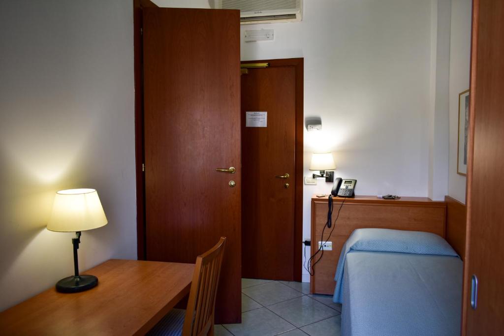 a bedroom with a bed and a desk with a lamp at Hotel Amyclae in Sperlonga