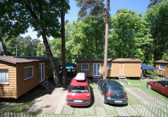 dos autos estacionados en un patio al lado de una cabaña en Wynajem domkow "Mala Holandia" en Krynica Morska