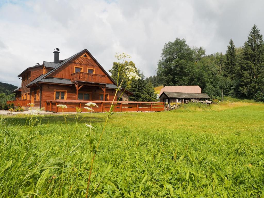 ein großes Holzhaus auf einem Grasfeld in der Unterkunft Pod Miloňovou in Velké Karlovice