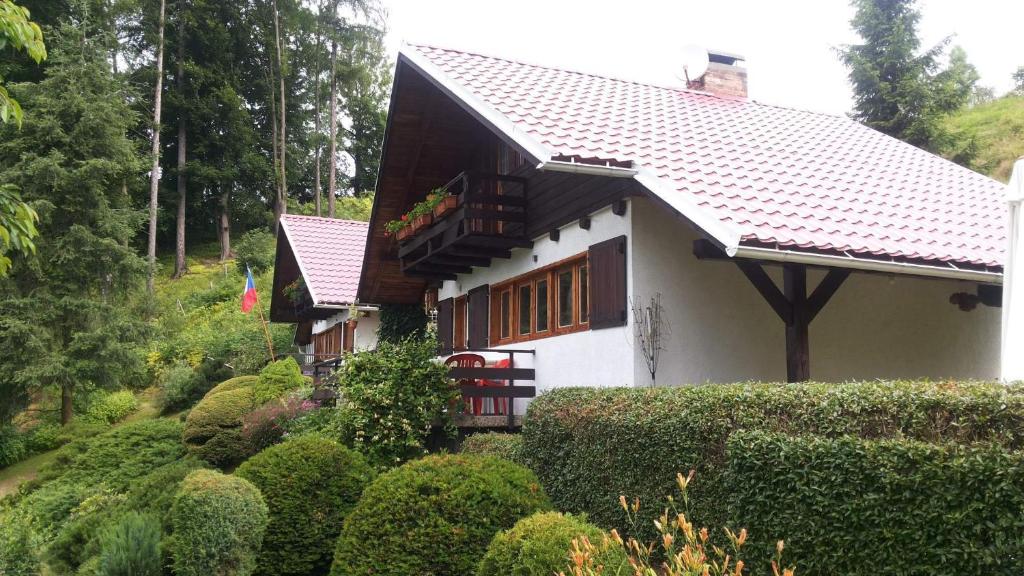 una casa blanca con techo marrón y algunos arbustos en Chata U Serifa, en Stružinec