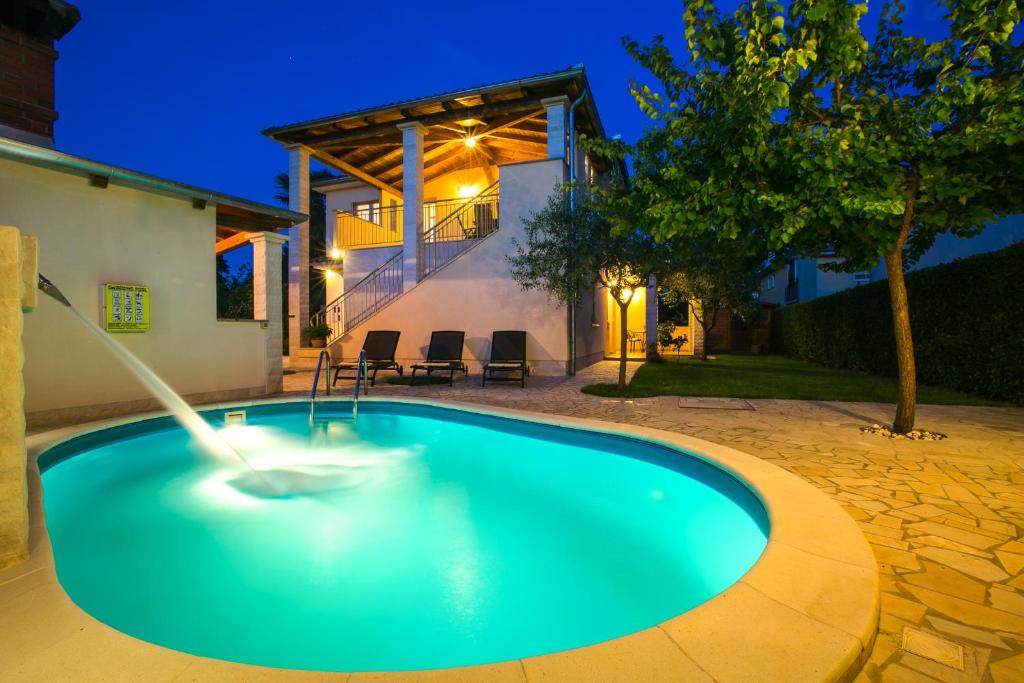 a swimming pool with a fountain in front of a house at Villa Cera Vodnjan in Vodnjan