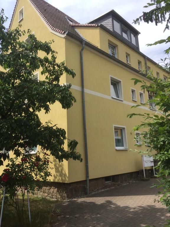 ein gelbes Gebäude mit schwarzem Dach in der Unterkunft Gertrud in Gaschwitz