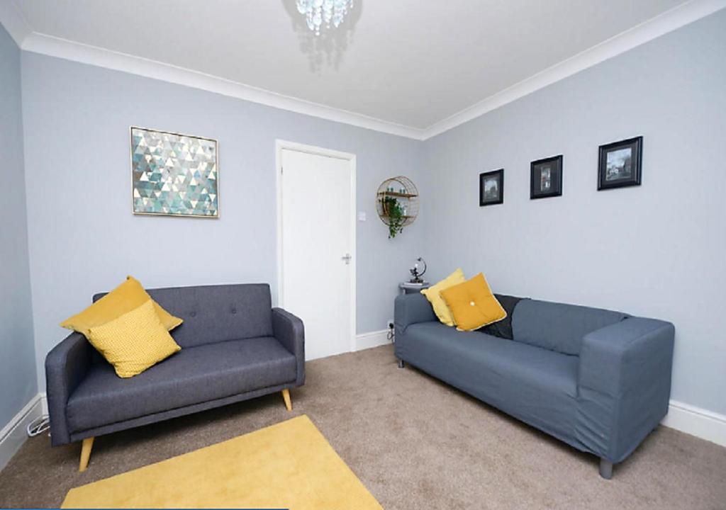 a living room with two blue couches and yellow pillows at Wingfield Lodge - Near Clay Cross in Chesterfield