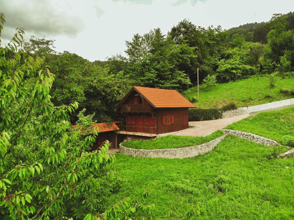 un petit bâtiment dans un champ herbeux à côté d'un chemin dans l'établissement Lazec Country House, à Plužnje