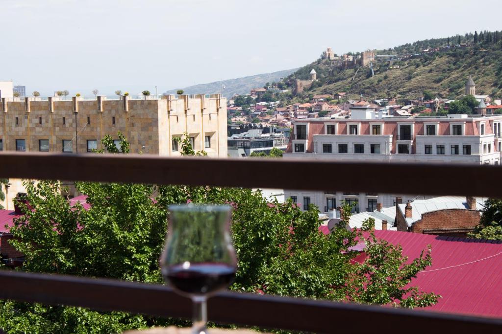 a glass of wine sitting on a balcony with a view at Diwan in Tbilisi City