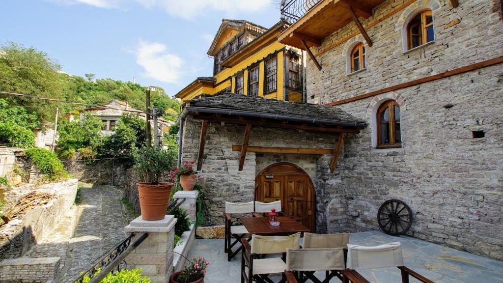 una casa de piedra con una mesa y sillas delante de ella en The Home of Diplomacy, en Gjirokastra