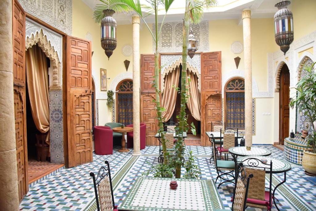 a room with tables and chairs and wooden doors at Riad Dar Zouhour in Rabat