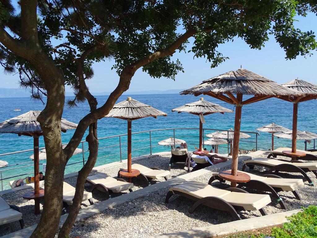 un grupo de tumbonas y sombrillas en la playa en Apartments Radović, en Labin