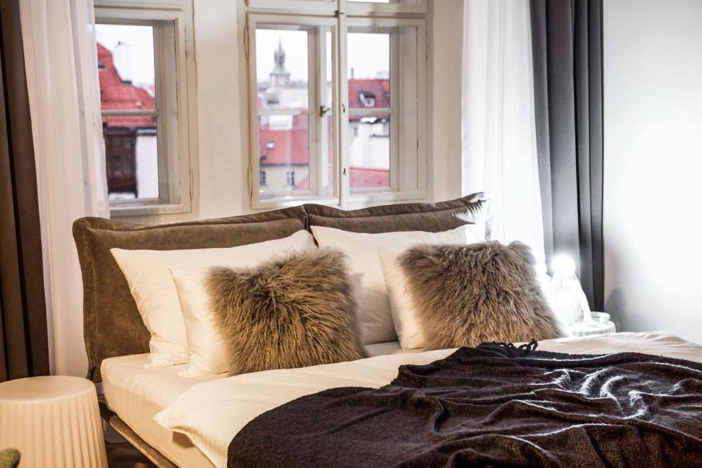 een slaapkamer met een bed met kussens en een raam bij Lazenska N4 Residence in Praag
