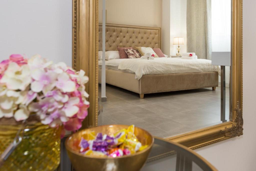 een slaapkamer met een spiegel en een tafel met bloemen bij Luxury Rooms Saint Jacob in Trogir